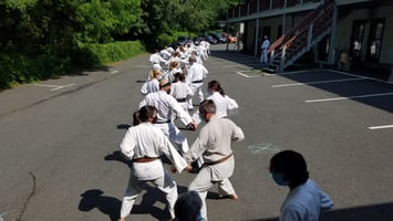 A group of karate students practicing outside in the summer